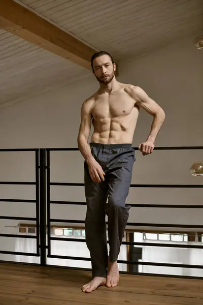 A shirtless man stands on a wooden floor, engaging in his morning routine. — Stock Photo