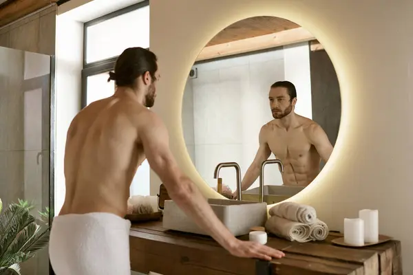Hombre haciendo su rutina de cuidado de la piel matutina en el espejo del baño. - foto de stock