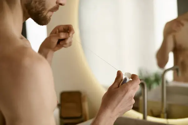 Homem sem camisa olha para o fio dental, rotina matinal em casa. — Fotografia de Stock