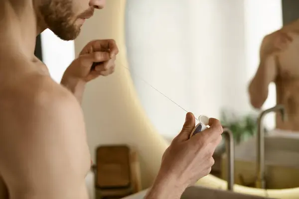 Hemdloser Mann starrt auf Zahnseide, Morgenroutine zu Hause. — Stockfoto