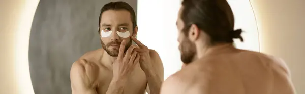 Um homem aplicando adesivos na frente de um espelho durante sua rotina matinal. — Fotografia de Stock