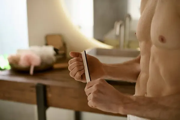 Shirtless man holding nail file in hand. — Stock Photo