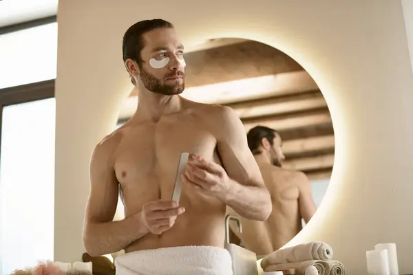 Un uomo in un asciugamano che usa lima per unghie davanti a uno specchio. — Foto stock
