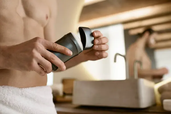 Un bel homme dans une serviette avec du déodorant après sa routine matinale. — Photo de stock