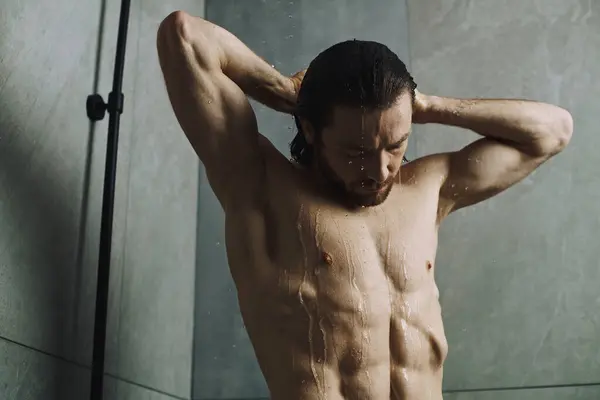 Shirtless man engaging in his morning standing in a shower. — Stock Photo