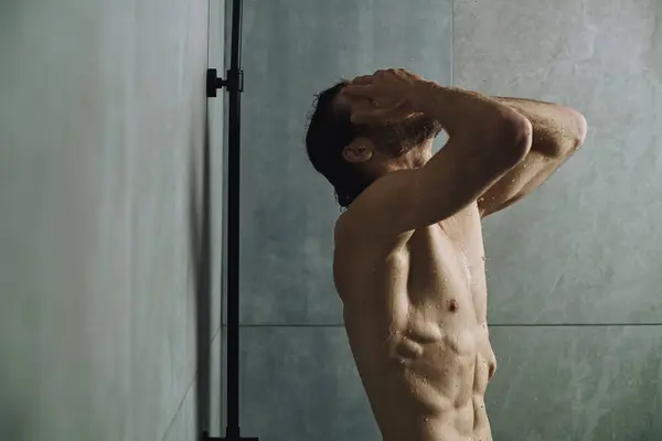 Мужчина без рубашки принимает душ и готовится к дню. — стоковое фото