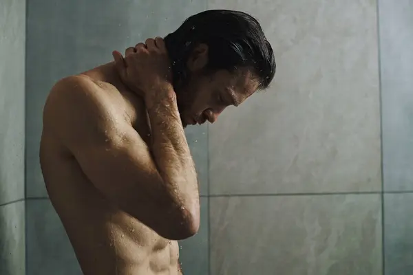 Uomo senza maglietta in bagno, si prepara per la giornata con routine mattutina e doccia. — Foto stock