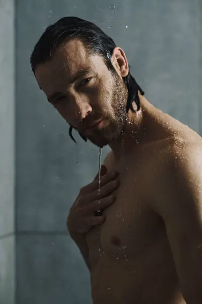 Um homem bonito limpa sob um chuveiro refrescante em sua rotina matinal. — Fotografia de Stock