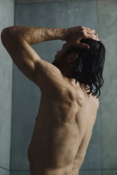Shirtless man stands by shower, engaging in morning routine. — Stock Photo
