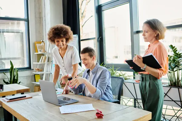 Diverse group of businesswomen gathered around a table, focused on a laptop screen. — Stock Photo