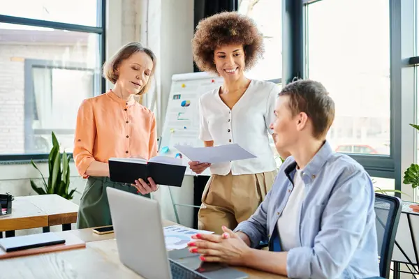 Grupo diverso de empresárias trabalhadoras reunidas em torno de um laptop em um espaço de escritório compartilhado. — Fotografia de Stock
