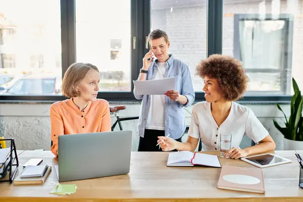 A group of hard-working, diverse individuals engage in business discussions around a table with laptops. — Stock Photo