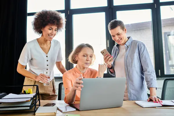 Diverse group around laptop in office meeting. — Stock Photo