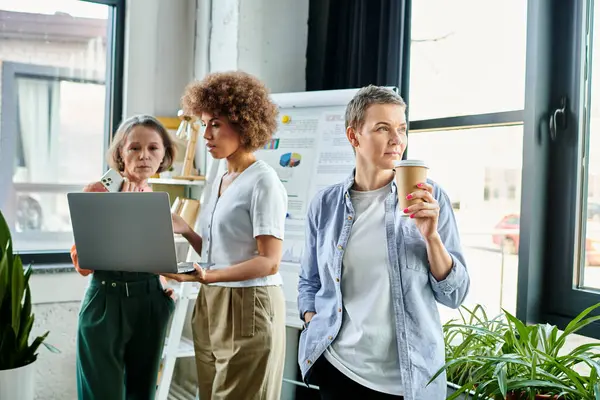 Diverse group of businesswomen gathered around a laptop in a collaborative workspace. — Stock Photo