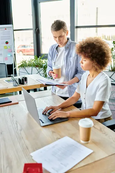 Two diverse women collaborating on a laptop at a table in a modern workspace. — Stock Photo