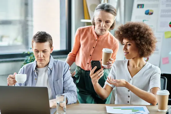 Diverse female professionals gathered around a laptop on a table in a collaborative workspace. — Stock Photo