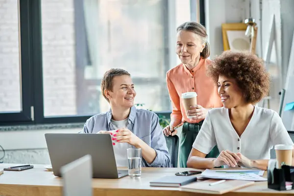 Diverso gruppo di professioniste impegnate in un incontro intorno a un computer portatile. — Foto stock