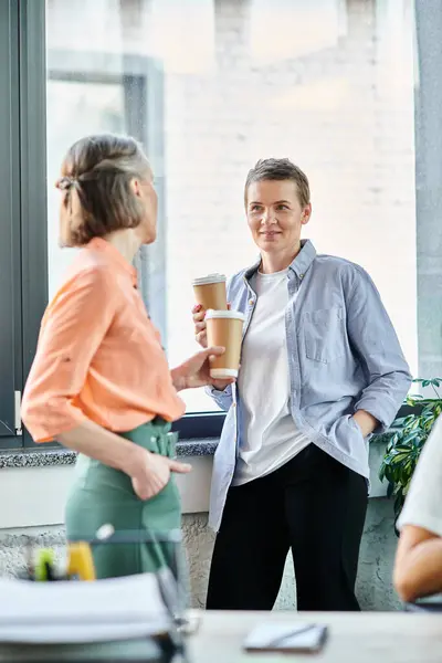 Two diverse businesswomen enjoying coffee together in a coworking space. — Stock Photo