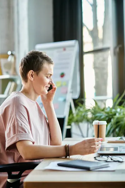 A woman sitting at a desk, engaged in conversation on a cell phone. — Stock Photo