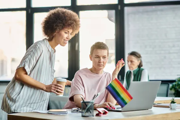 Dedicated diverse businesswomen working together on project in office, pride flag. — Stock Photo