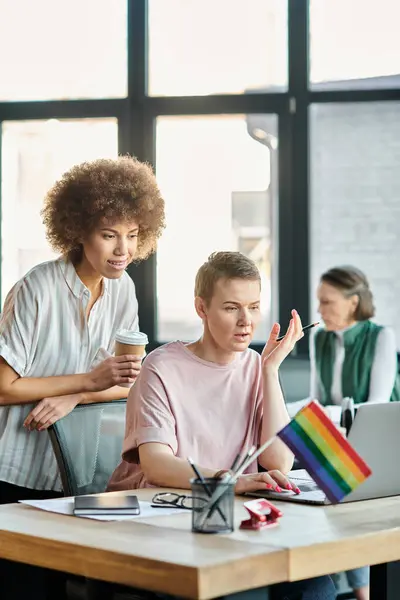 Devoted diverse businesswomen working together on project in office, pride flag. — Stock Photo