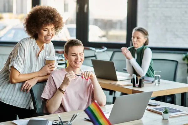 Joyous diverse businesswomen working together on project in office, pride flag. — Stock Photo