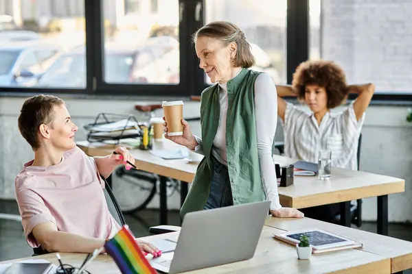 Elegant diverse businesswomen working together on project in office, pride flag. — Stock Photo