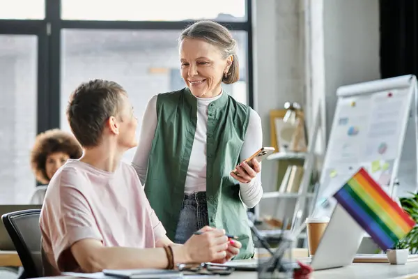 Merry diverse businesswomen working together on project in office, pride flag. — Stock Photo