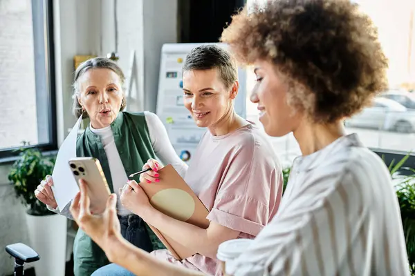 Diverso grupo de profesionales femeninas que colaboran con un teléfono. - foto de stock