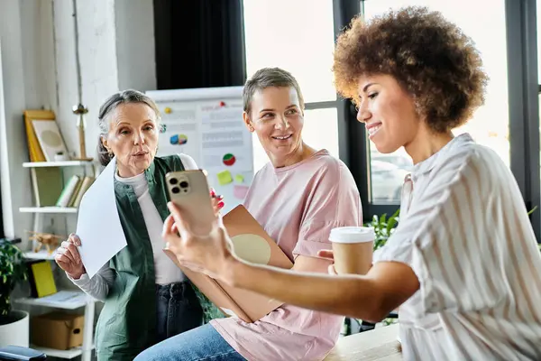 Diverse businesswomen engaged around table with cell phone. — Stock Photo