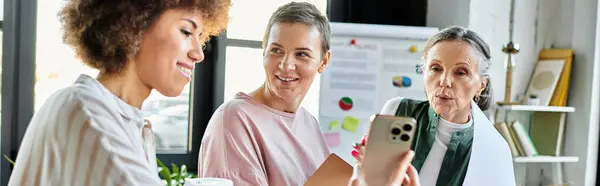 Cheerful diverse businesswomen engaged with cell phone. — Stock Photo