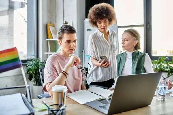 A group of diverse female professionals collaborating around a laptop in a modern office setting. — Stock Photo