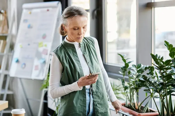 Attractive businesswoman, in a green vest, engrossed in her cell phone. — Stock Photo