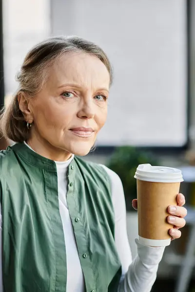 Eine Frau, elegant und konzentriert, hält eine dampfende Tasse Kaffee in der Hand. — Stockfoto