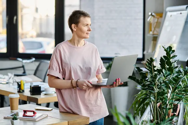 Виділена бізнес-леді зосереджена на своєму ноутбуці в сучасному офісі. — стокове фото