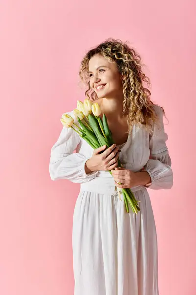 Woman in white dress holding tulip bouquet, embodying elegance and spring fever. — Stock Photo
