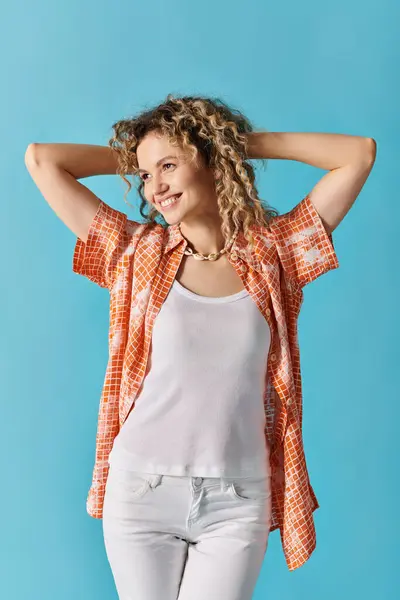 Mujer de pelo rizado en jeans blancos y camisa naranja en una pose. - foto de stock