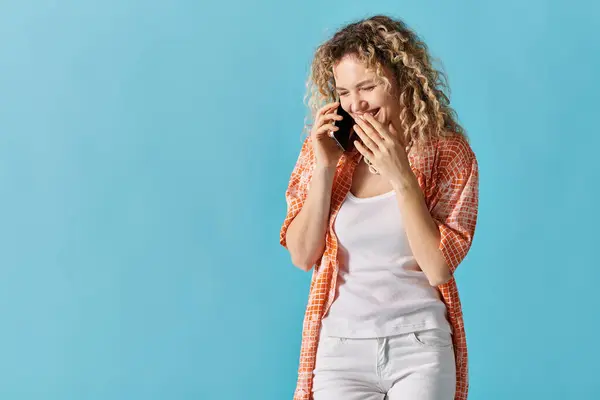 Mulher com cabelo encaracolado conversando no telefone contra fundo azul brilhante. — Fotografia de Stock