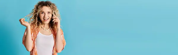 Woman with curly hair talking on cell phone against vibrant blue background. — Stock Photo
