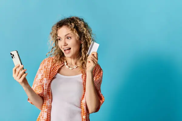 Woman with curly hair holding phone and credit card. — Stock Photo