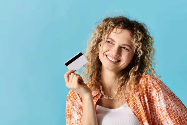 Giovane donna con i capelli ricci detiene con fiducia la carta di credito. — Foto stock