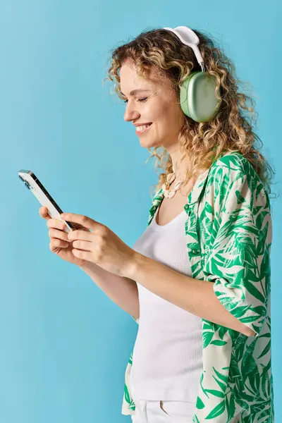 Femme aux cheveux bouclés immergés dans la musique à travers écouteurs et téléphone. — Photo de stock