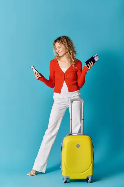 Donna elegante con valigia gialla che invia SMS al telefono — Foto stock