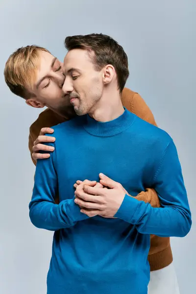 Amar casal gay em trajes casuais posando juntos no fundo cinza. — Fotografia de Stock
