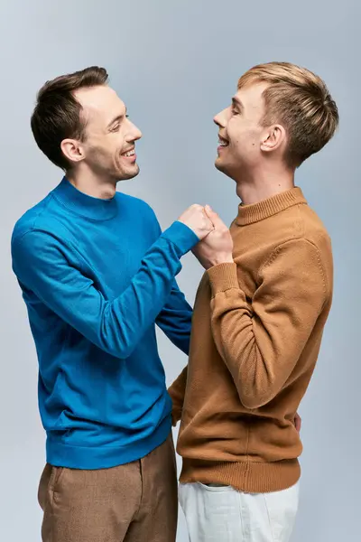 Two men in casual attire stand side by side holding hands. — Stock Photo