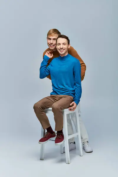 Dos hombres con atuendo casual posando sobre un fondo gris. - foto de stock