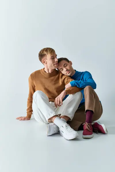 Casual gay couple happily pose on gray backdrop. — Stock Photo