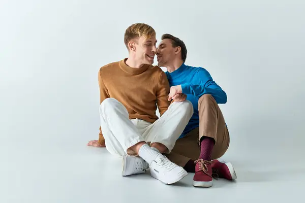 Two men seated, arms entwined in love and camaraderie. — Stock Photo