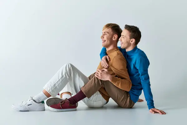 Two men sitting embraced on the ground. — Stock Photo