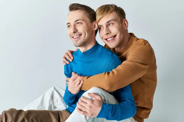 Two men in casual attire sitting on the floor hugging each other. — Stock Photo